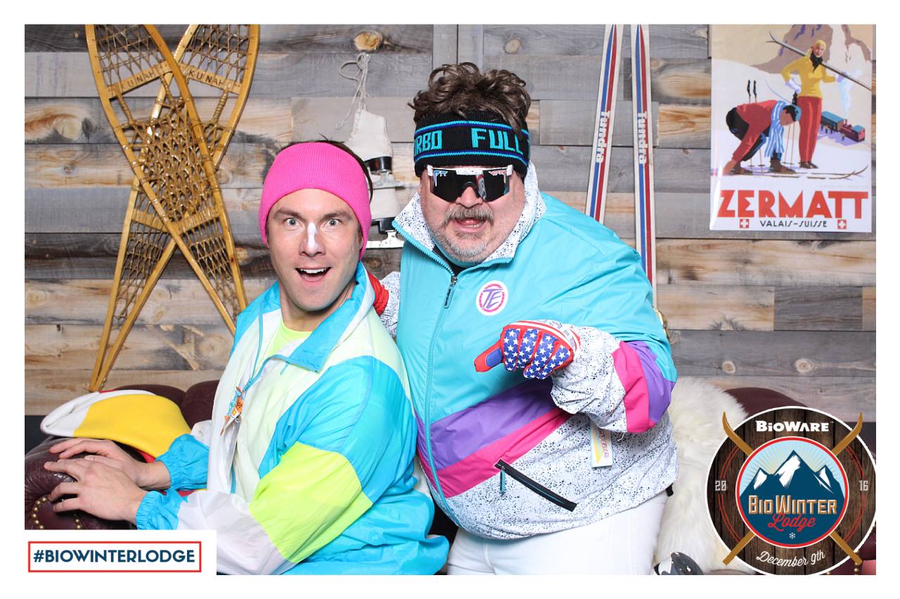 Two men having fun at a Bioware event using a photo booth and dressed in ski clothing.